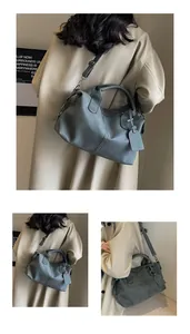Detail der graublauen matten Boston Tasche mit verstellbarem Gurt und Dekorativem Anhänger