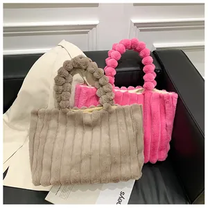 Détail de sacs cabas en peluche avec texture à rayures verticales et poignées à pompons