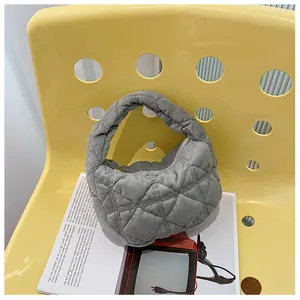 Detail van grijze gewatteerde hobo-tas met wolkentextuur op moderne gele stoel