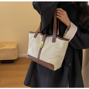 Detailansicht einer Vintage Canvas-Tragetasche mit braunem Lederbesatz und Goldverschluss