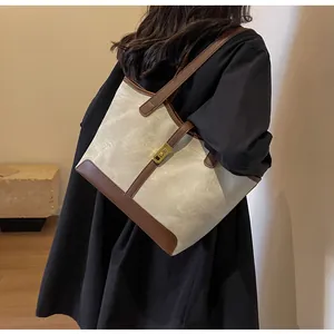 Seitenansicht einer Canvas-Tote-Bag mit braunem Lederbesatz und Metallverschluss am Modell