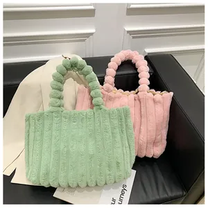 Détail de sacs fourre-tout en peluche rayée verte et rose avec poignées à perles douces