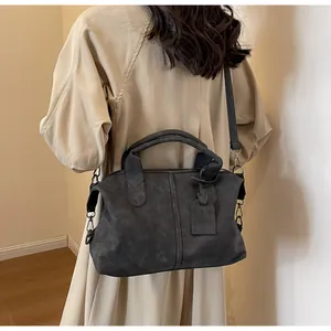 Dunkelgraue Vintage-Boston-Tasche mit Henkeln und Gurt am Model in der Seitenansicht