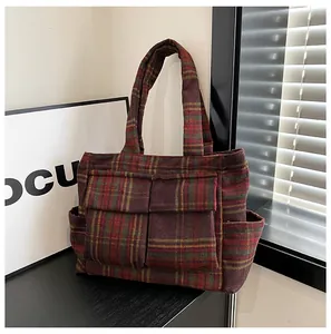 Detail view of the red plaid faux shearling tote bag featuring functional front pockets