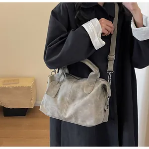 Graue Vintage Handtasche mit Griffen und verstellbarem Riemen getragen von einem Model