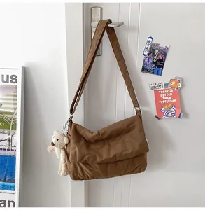 Detail van bruine gewatteerde crossbodytas met hartpatroon en pluche beer hanger