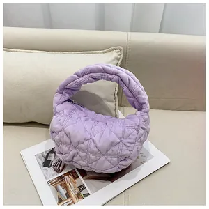 Detail van paarse gewatteerde hobo-tas met wolkachtige textuur op een beige bank