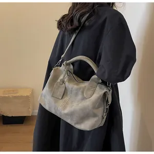 Detailansicht der grauen Boston-Tasche im Vintage-Stil mit matter Lederstruktur und Anhänger