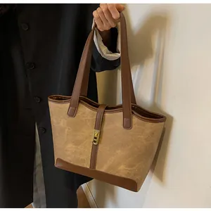 Details der Vintage-Canvas-Tasche mit braunem Lederbesatz und goldener Schnalle am Modell