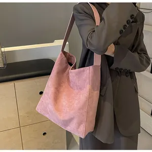 Rosa Tragetasche aus Wildleder mit breitem Schultergurt getragen in minimalistischem Raum
