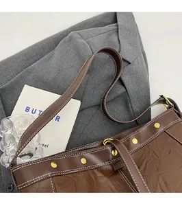 Detail of brown PU leather tote with pleated texture and stylish golden rivet studs