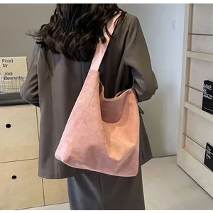 Detail view of pink suede hobo bag with a wide shoulder strap worn by a model