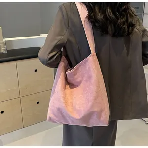 Detail of pink suede tote bag with wide shoulder strap worn with a casual gray blazer