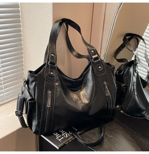 Detail of black faux leather tote featuring silver zippers, rivets and adjustable shoulder strap
