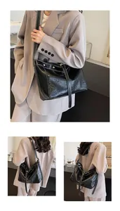 Detail of black PU leather tote with white contrast stitching and gold metal studs