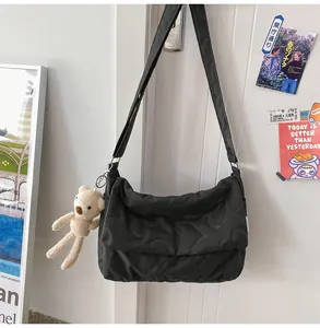 Detail van zwarte crossbodytas met hartstiksel en een schattige teddybeer hanger