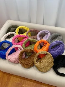 Gewatteerde mini cloud handtassen in diverse kleuren op een bank voor een modern interieur