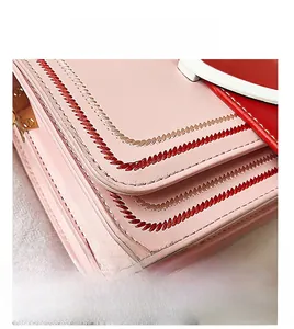 Dettaglio macro della borsa in pelle rosa con ricami rossi e finiture in metallo oro