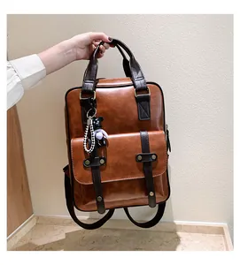 Detail of vintage brown backpack with dark contrast straps and a small bear pendant