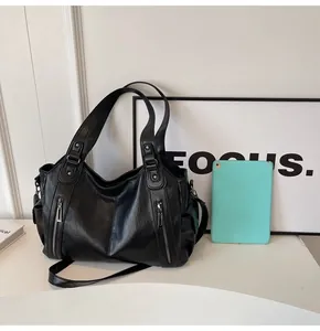 Detail of black leather tote bag featuring side pockets and reinforced rivet straps