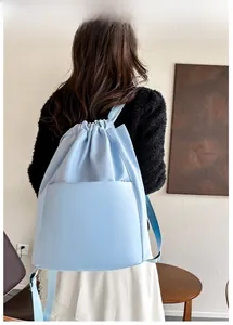 Rear view of a light blue nylon drawstring backpack worn by a model for travel and yoga