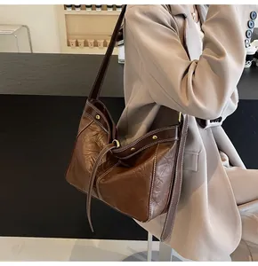Detailed shot of brown PU leather tote bag featuring contrast stitching and gold rivets