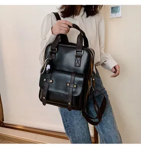 Detail of vintage black PU leather backpack with contrast straps and panda charm