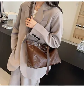 Detail of dark brown tote bag showing retro texture, white stitching and gold studs