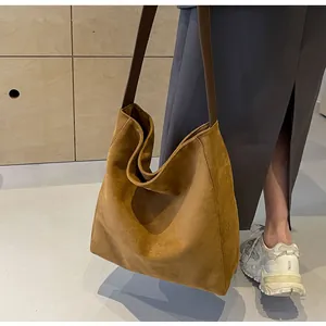Detailed texture of brown suede tote bag with contrast shoulder strap on model