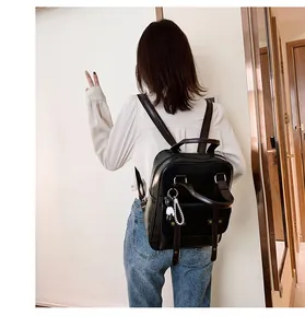Detail of vintage black leather backpack showing the adjustable straps and bear charm detail