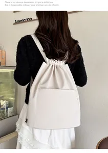 Lifestyle view of a minimalist cream nylon drawstring backpack with large front pocket