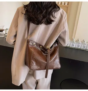 Detail of vintage brown textured leather tote with contrast white stitching and gold hardware