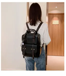 Detail of vintage black leather backpack with brown straps and cute white plush charm