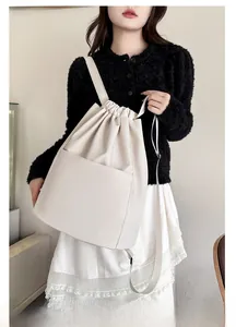 Detail of off-white minimalist drawstring backpack in matte leather texture with front pocket