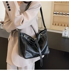 Detail of black pleated PU leather tote bag featuring white contrast stitching and rivets