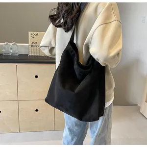 Detail showing the slouchy fit and draped silhouette of a large black canvas tote bag