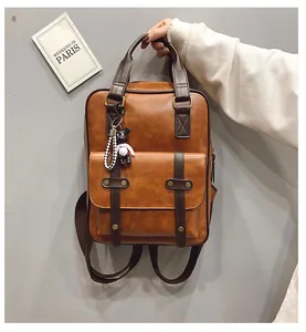 Detail view of vintage brown leather backpack with bear charm and bronze stud accents