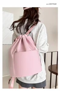 Close-up of lightweight pink nylon drawstring backpack showing large front pocket detail