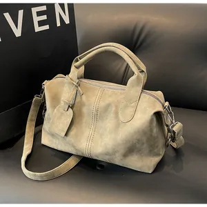 Detailansicht der olivgrünen Boston Bag aus Wildleder mit Metallreißverschluss und Tag
