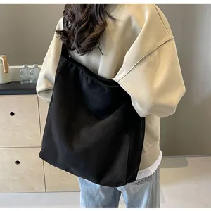 Rear view of model wearing a large black minimalist tote bag with wide shoulder strap