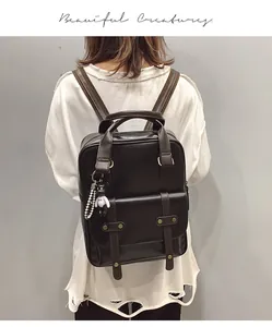 Detail view of vintage black leather backpack featuring buckles and a cute bear charm