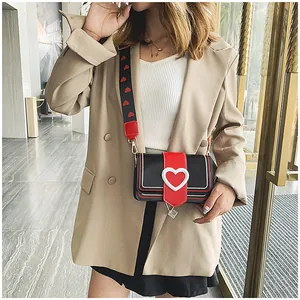 Dettaglio della piccola borsa a tracolla alla moda con fibbie a cuore e tracolla larga