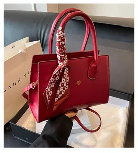 Detail der roten Brauthandtasche mit Fashion-Text, Herzlogo und gemustertem Seidenschal
