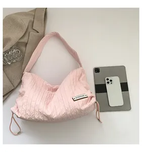 Close-up of pink pleated fabric tote bag with superior label and drawstring detail