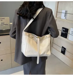 Detail of off-white tote bag with pleated leather texture and metal ring buckle