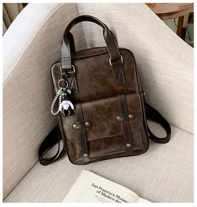 Detail shot of vintage dark brown backpack with a cute teddy bear charm and gold hardware
