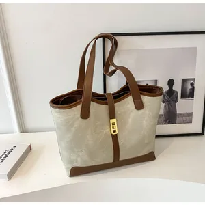 Nahaufnahme der Canvas-Tasche mit braunem Lederbesatz und goldenem Rechteck-Metallverschluss