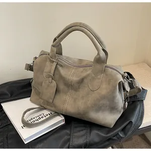 Detail der taupefarbenen Boston Bag mit Ziernähten auf einer schwarzen Lederjacke