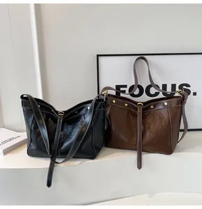 Detail of black and brown oversized PU leather tote bags with white contrast stitching
