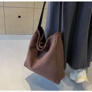 Close-up of a brown suede hobo tote bag featuring a wide strap and minimalist design